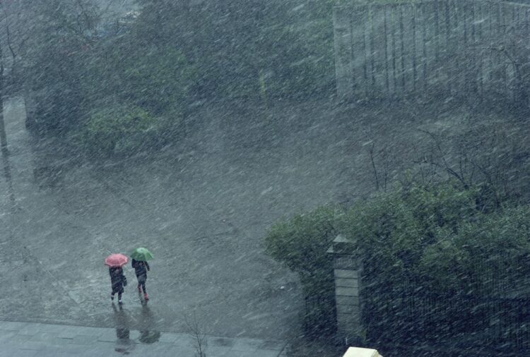 Dve osebi z dežniki v dežju