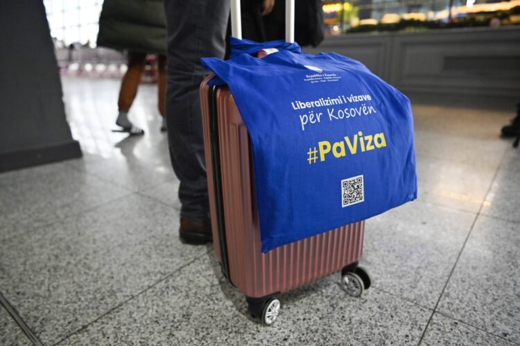 potnik na letališču z napisom za liberalizacijo viz za Kosovo