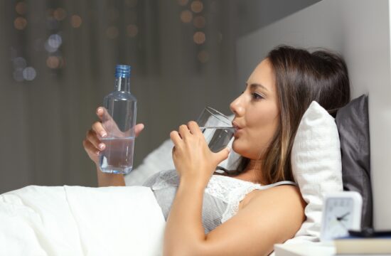 ženska pije vodo v postelji