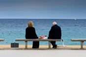Starejši par sedi na obali