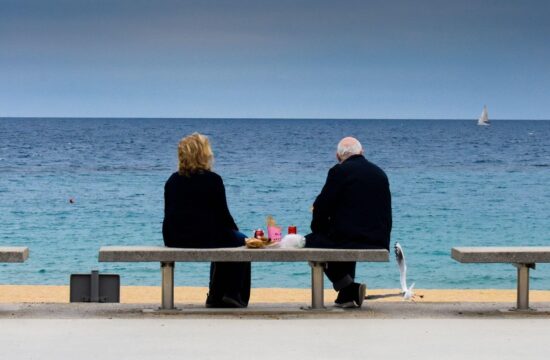 Starejši par sedi na obali