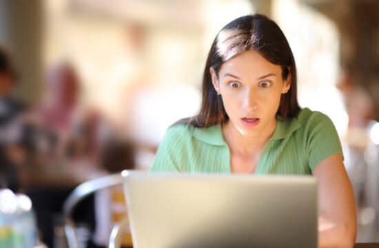Presenečena ženska pred prenosnim računalnikom