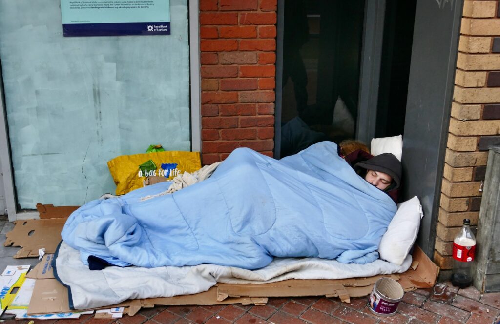 mlada brezdomca spita zunaj na vzmetnici