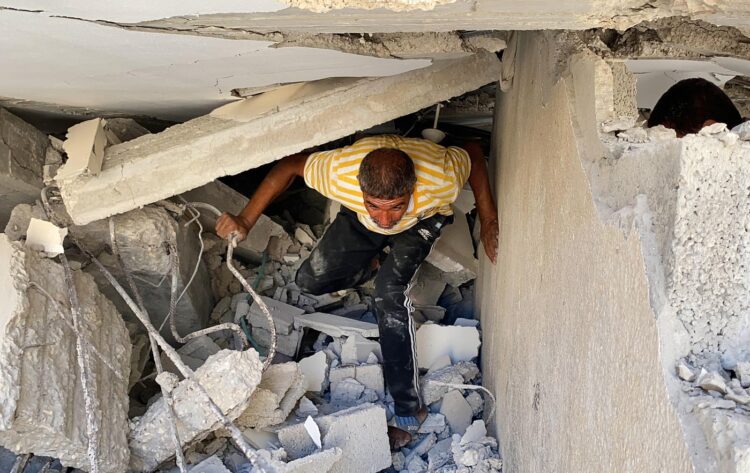 Moški preiskujejo ruševine hiše, v kateri je živela sestra vodje Hamasa