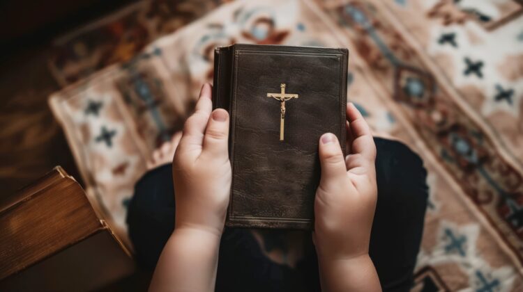 otrok v roki drži sveto pismo