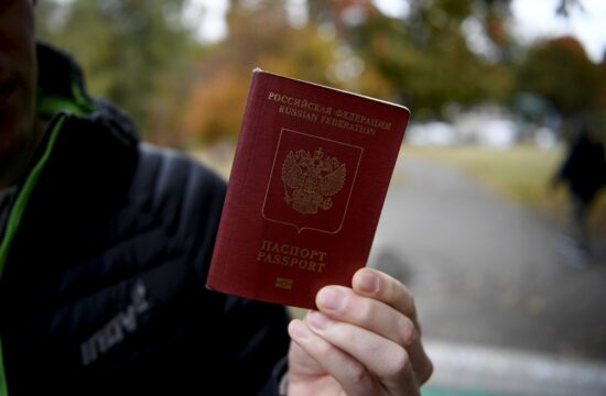 moški v roki drži ruski potni list