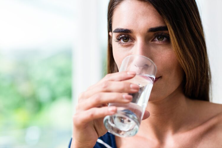 Mlada ženska pije kozarec vode