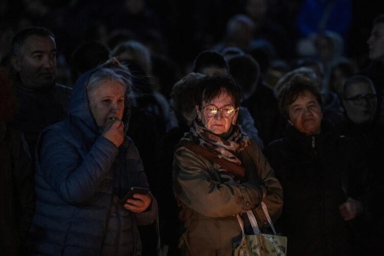 Ljudje prižigajo sveče in nosijo cvetje pred železniško postajo v Novem Sadu